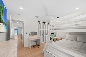 A modern bedroom with a bunk bed, desk, and a view of the outdoors.