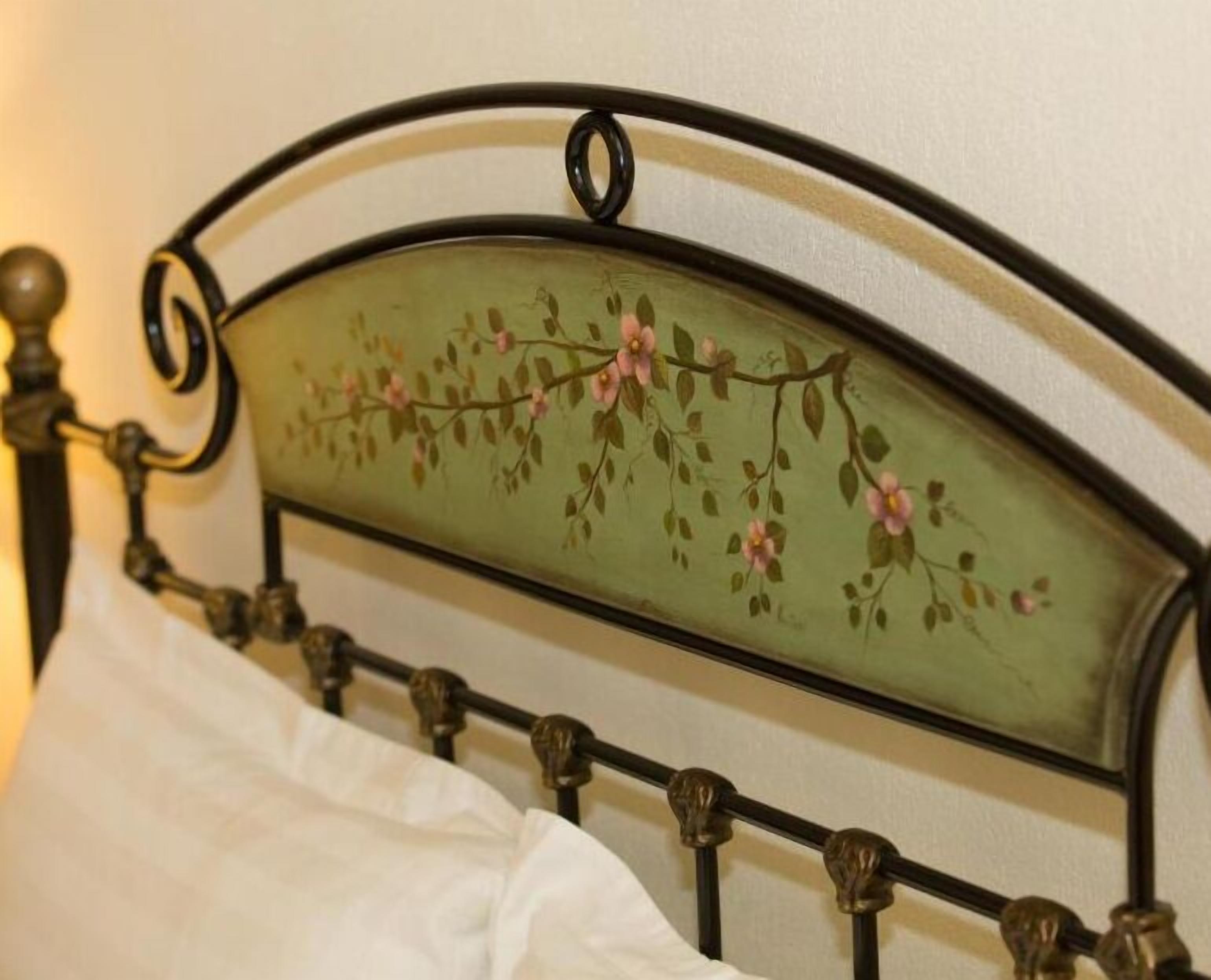 Una cama con estructura metálica y un cabecero decorativo con motivos florales.