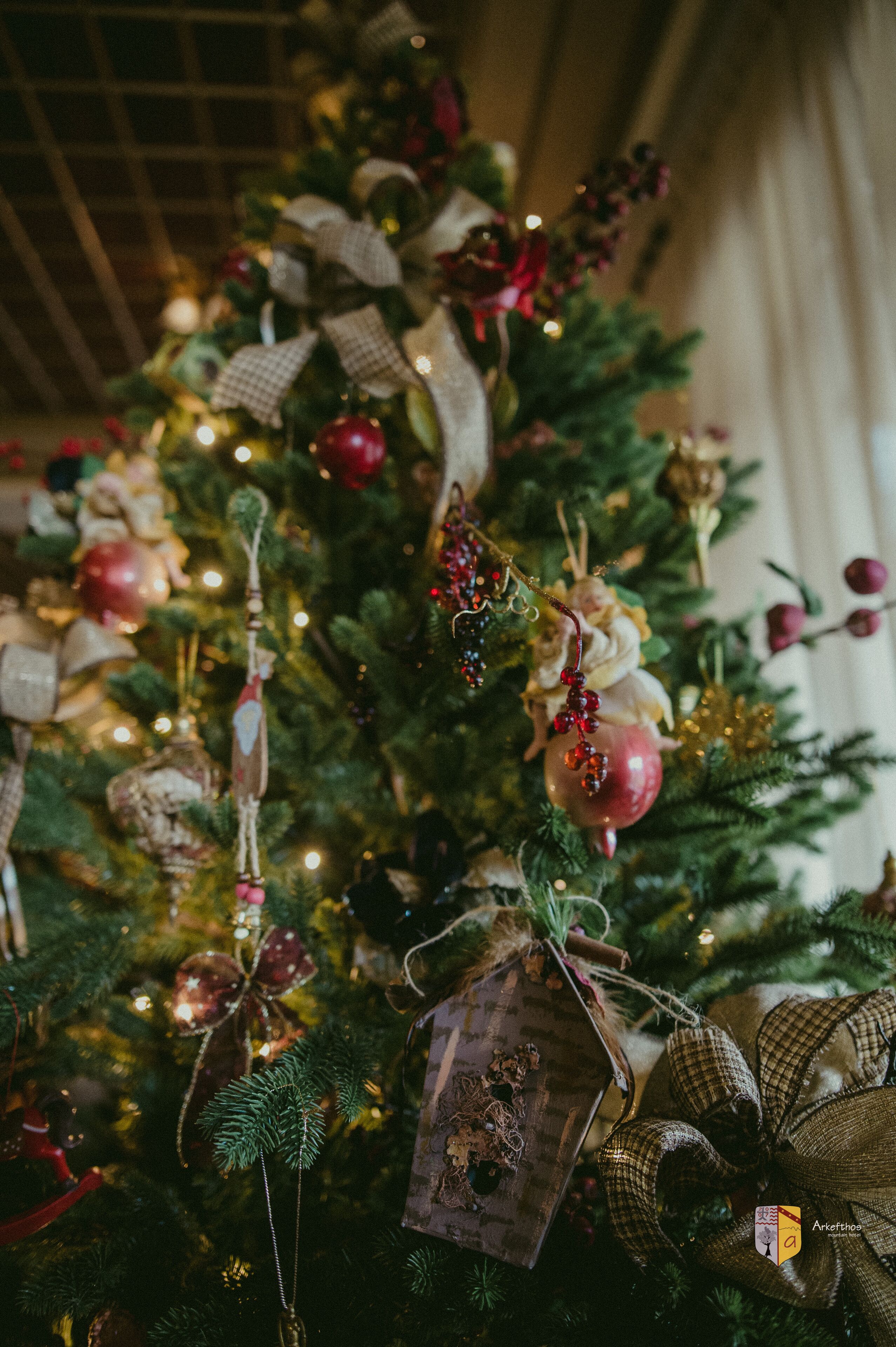 Een kerstboom versierd met diverse decoraties en versieringen.
