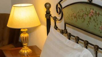 Un lit avec un oreiller blanc, une tête de lit en laiton et une lampe de table avec un abat-jour jaune.