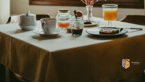 A breakfast table with a teapot, cup, jar, and plate with toast, set against a window with a mountain view. - Arkefthos Mountain Hotel (Zagori)