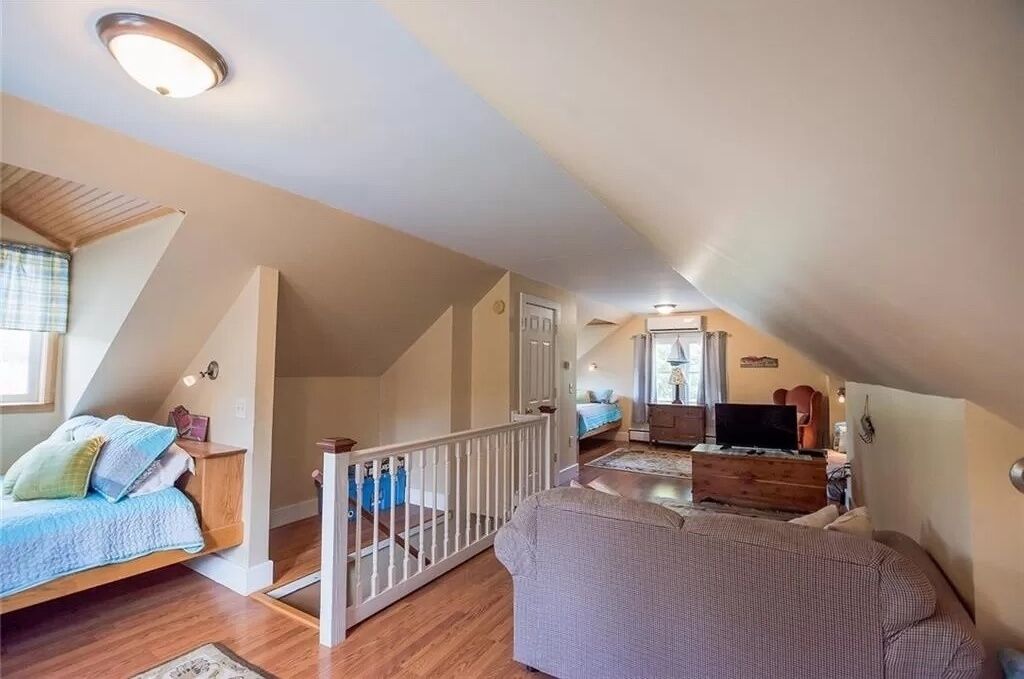 A spacious loft bedroom with a large bed, a seating area with a sofa, and a television.