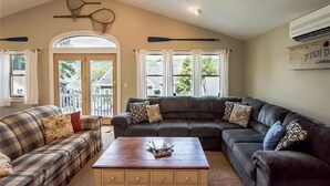 A cozy living room with a dark brown leather couch, a plaid sofa, and a wooden coffee table. - Keuka East: Spacious & Comfy (Penn Yan)