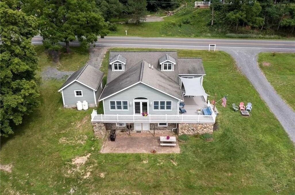 A two-story house with a porch, a small detached garage, and a front yard with outdoor seating.