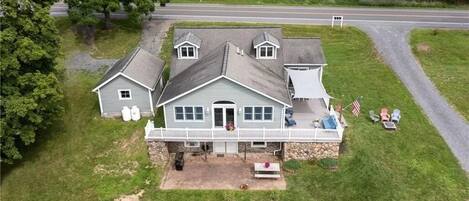 A two-story house with a porch, a small detached garage, and a front yard with outdoor seating.
