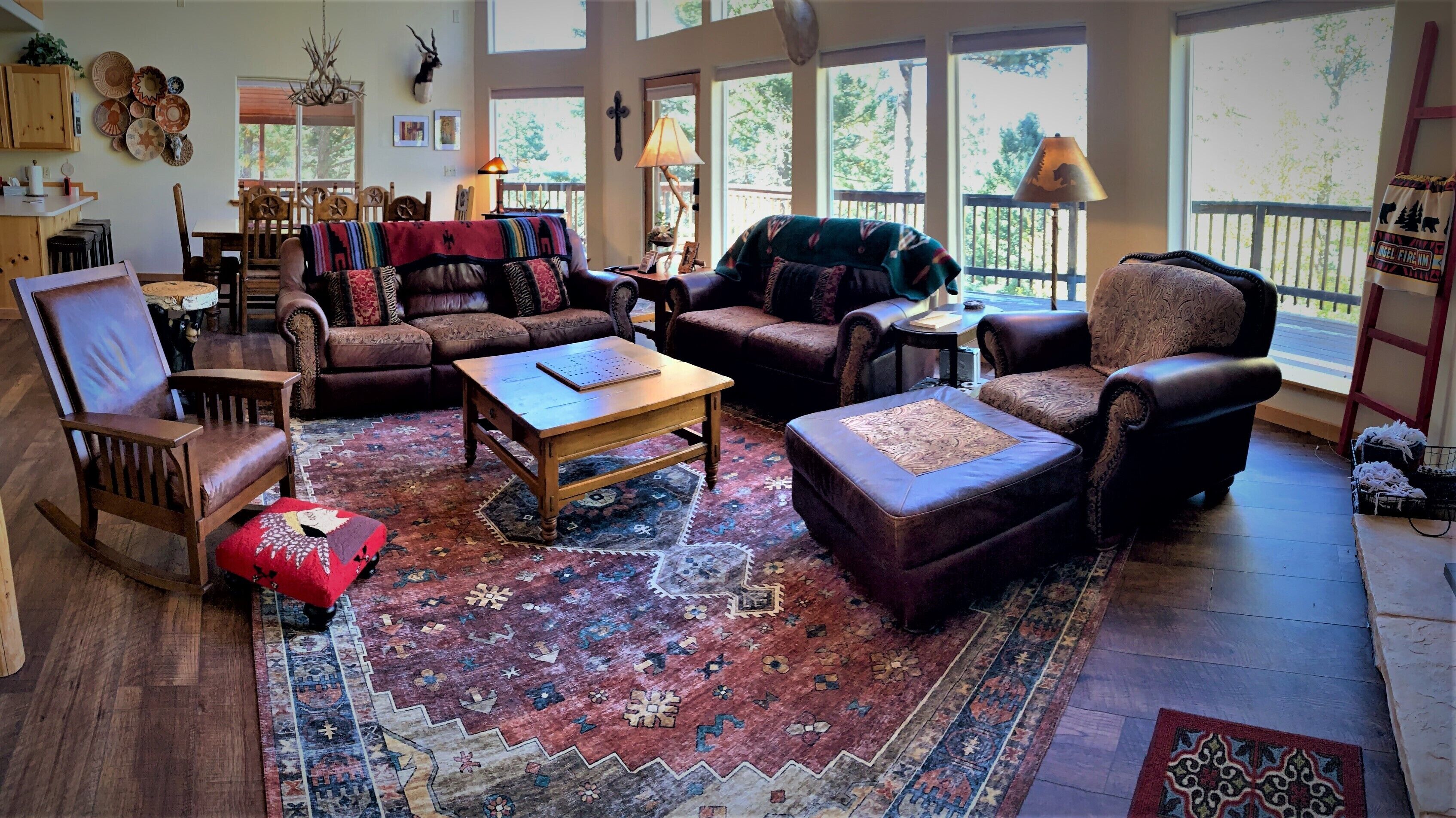 Un salon spacieux agrémenté d’un grand tapis, de nombreux sièges, dont un canapé et des fauteuils, d’une table basse en bois et d’une vue dégagée grâce à de grandes fenêtres.