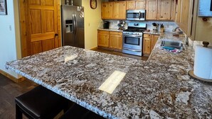 Una cocina con encimeras de granito, armarios de madera, electrodomésticos de acero inoxidable y una puerta de madera.