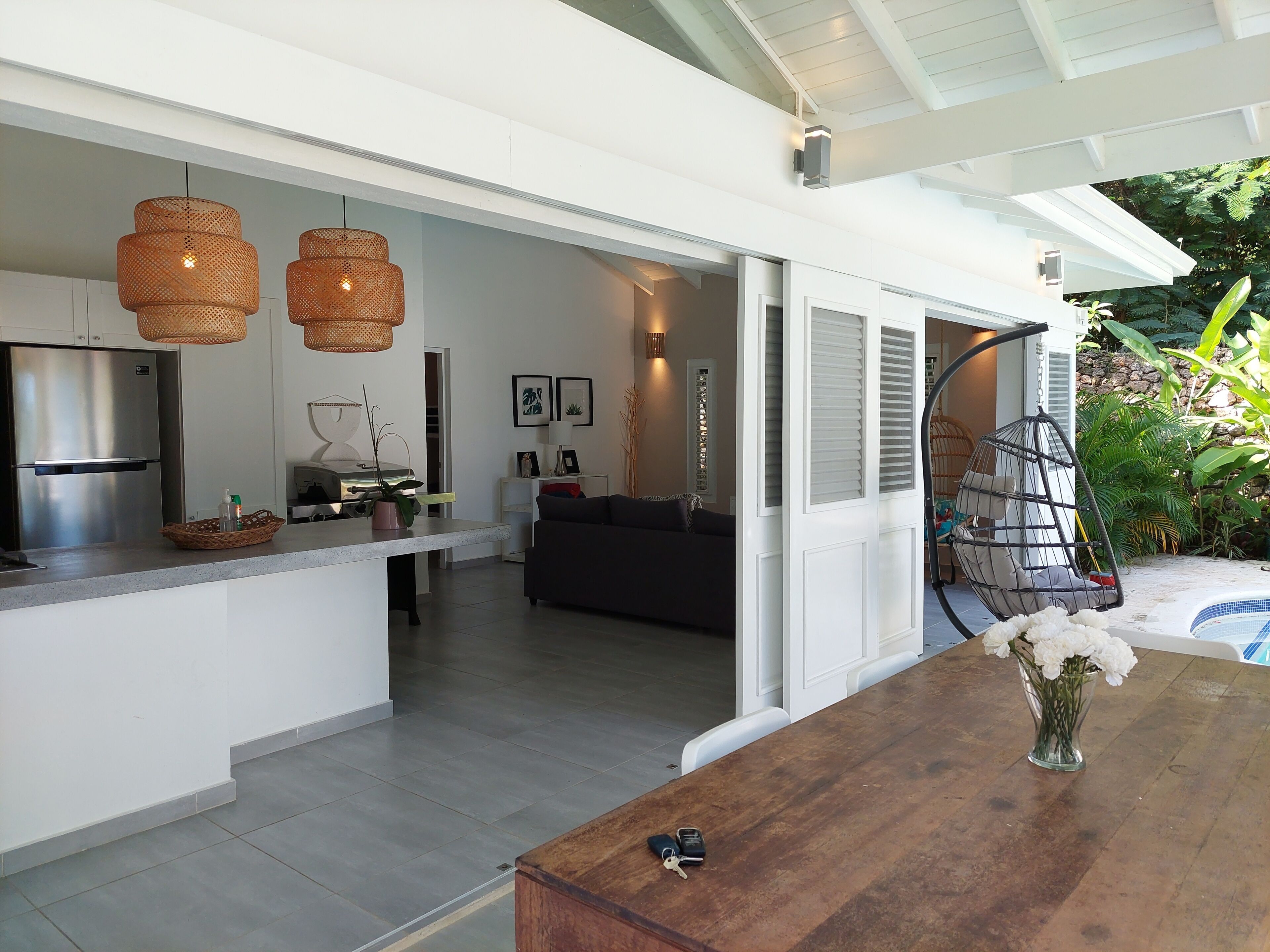 Una cocina moderna con una isla central, un comedor con mesa de madera y una sala de estar con sofá.