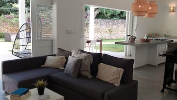 A modern living room with a sectional sofa, a coffee table, and a dining area with a table and chairs.