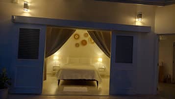 Un dormitorio moderno con una cama centrada bajo un techo inclinado, flanqueada por dos mesitas de noche con lámparas.