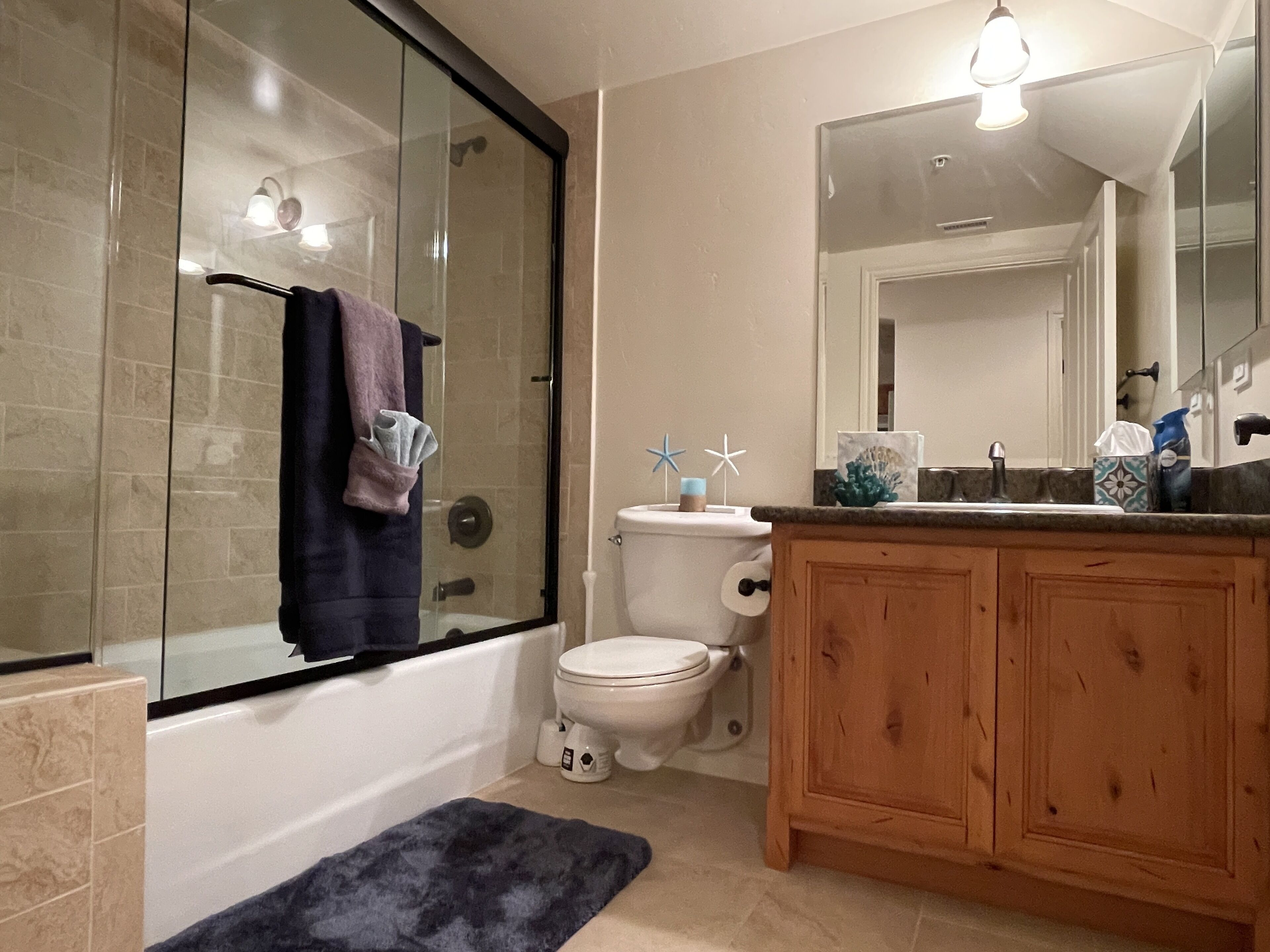 A bathroom with a glass-enclosed shower, a white toilet, and wooden cabinets.