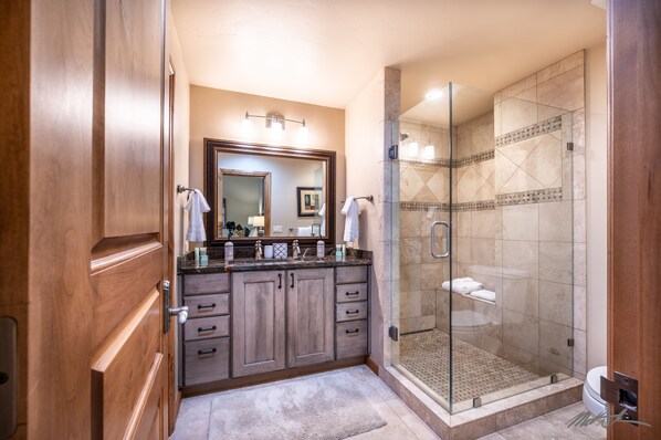 A bathroom with wooden cabinets, a double sink, a glass-enclosed shower, and a large mirror. - Superb 3 BR Townhome in Cascade Village w/Bikes, Shared Spa, Sauna & Cold Plunge (Vail)