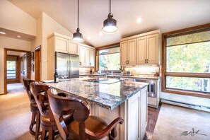 A modern kitchen with a large island, stainless steel appliances, and wooden cabinets.