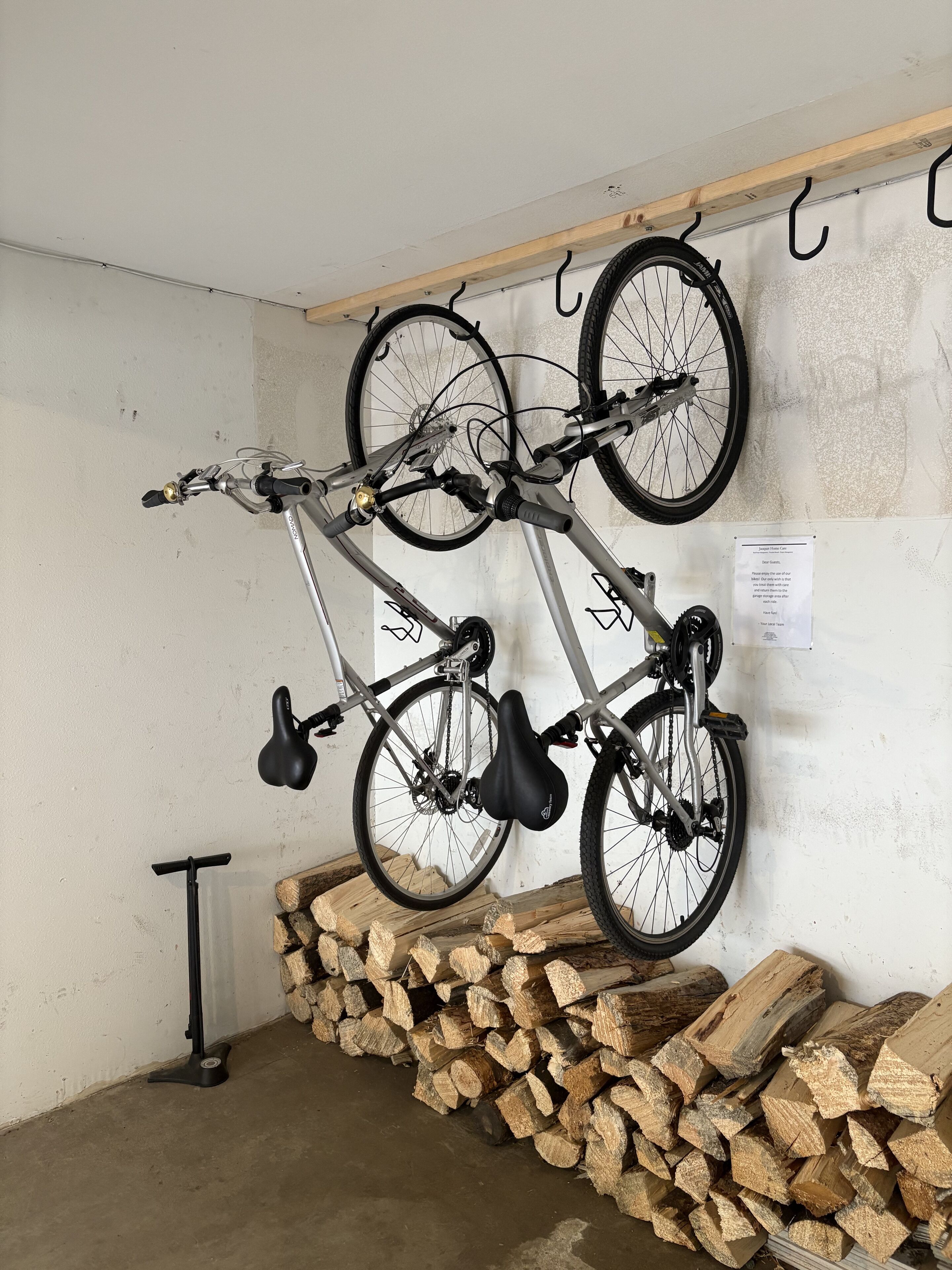 Una bicicleta penjada en un suport de paret, una pila de llenya i una làmpada de peu.