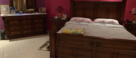 Un dormitorio con una cama de madera, un aparador, un espejo y dos cuadros en la pared.