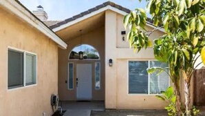 A two-story house with a covered entryway, a small garden, and a visible garage door. - Family & Military-Friendly 4BR/2BA 
Near Camp Pendleton, Legoland & Coastal Fun (Oceanside)