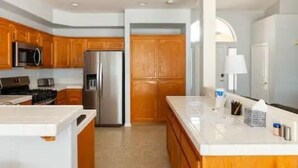 A modern kitchen with wooden cabinets, stainless steel appliances, and a white countertop. - Family & Military-Friendly 4BR/2BA 
Near Camp Pendleton, Legoland & Coastal Fun (Oceanside)