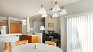 A modern kitchen with a central island, a dining area with a round table, and a seating arrangement. - Family & Military-Friendly 4BR/2BA 
Near Camp Pendleton, Legoland & Coastal Fun (Oceanside)