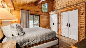 Une chambre à coucher dans un chalet en bois, avec un lit, une table de chevet, une lampe et une armoire.
