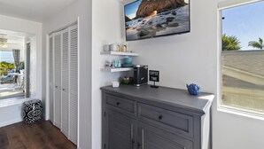Ett modernt rum med en tv som visar en strandvy, en kaffestation och utsikt över omgivningarna.