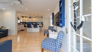 A modern living room with a sofa, a dining area with a table and chairs, and a kitchen in the background. - Beautiful Lavallette Home - Perfect for Family and Friends (Lavallette)
