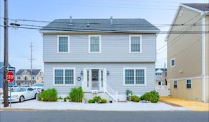 Stunning two-story home with a central entrance and white porch, featuring two windows on each floor.