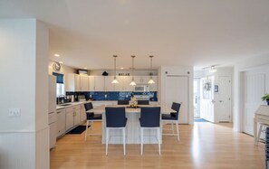 Une cuisine moderne avec des armoires blanches, un pare-feu bleu et des luminaires suspendus.