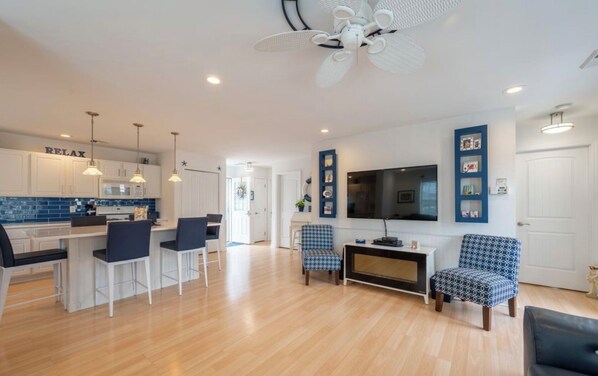 Cozy living space with a central kitchen, seating area, and flat-screen TV.