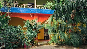 Un patio con un puente colorido, abundante vegetación y un camino de grava.