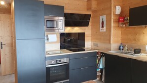 Una cocina moderna con armarios de madera, microondas integrado, horno y un lavamanos con escurreplatos.