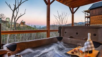 A hot tub with a wooden deck, a bottle, glasses, and macarons on a tray.