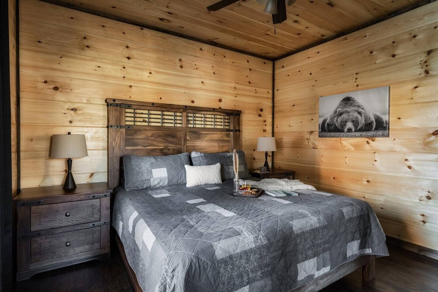 Ein Schlafzimmer einer Holzhütte mit einem Bett, zwei Nachttischen und einem Kopfteil.