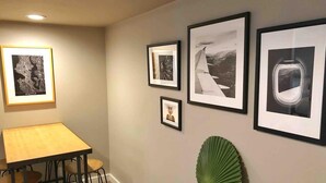A hallway with a dining area featuring a table and chairs, and several framed pictures on the wall. - Seattle Launchpad - Cozy and Modern 2 BR Guest Suite (Seattle)