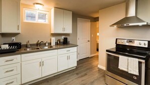 A modern kitchen with white cabinets, a stainless steel sink, a built-in oven, and a window above the sink. - Seattle Launchpad - Cozy and Modern 2 BR Guest Suite (Seattle)