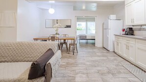 A modern kitchen with white cabinets, a dining area with a table and chairs, and a cozy living area with a sofa.