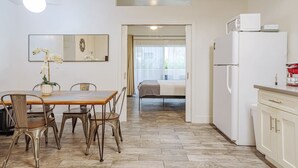 A compact kitchen with a dining area, a refrigerator, and a microwave.