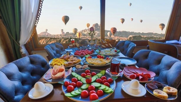 Ein Esstisch mit verschiedenen Speisen und Blick auf Heißluftballons.