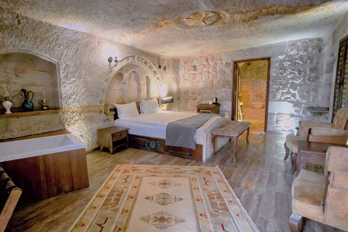 Ein Schlafzimmer mit Stehwänden, einem Bett, Nachttischen, einer Bank und einem Sessel.