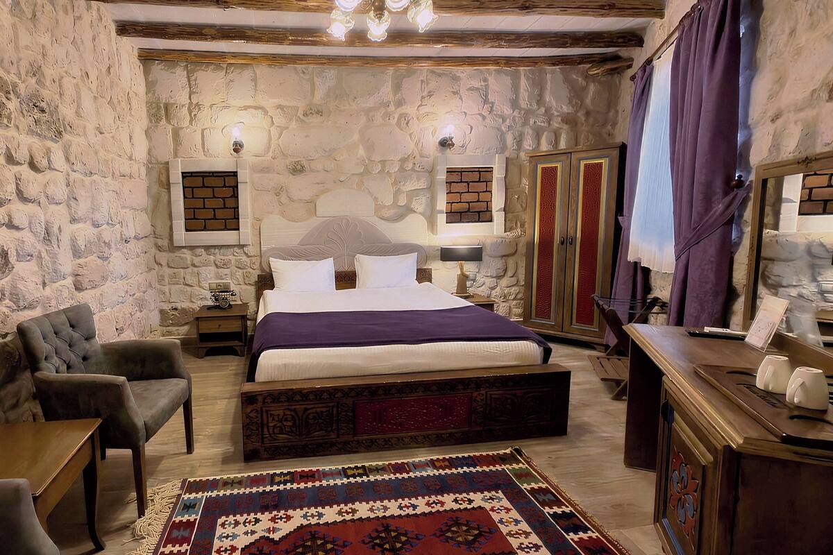 Ein Schlafzimmer mit Stehwänden, einem Bett, Nachttischen, einem Sessel, einer Kommode und einem Spiegel.