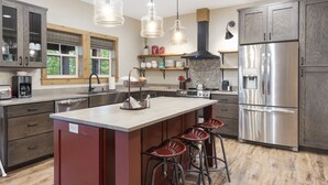 A modern kitchen with a central island, stainless steel appliances, and pendant lighting.