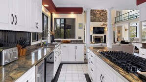 Una cocina moderna con armarios blancos, encimeras de granito y una isla grande con estufa a gas.