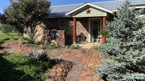 A rustic stone building with a metal roof, a large wheel, and a star on the front.