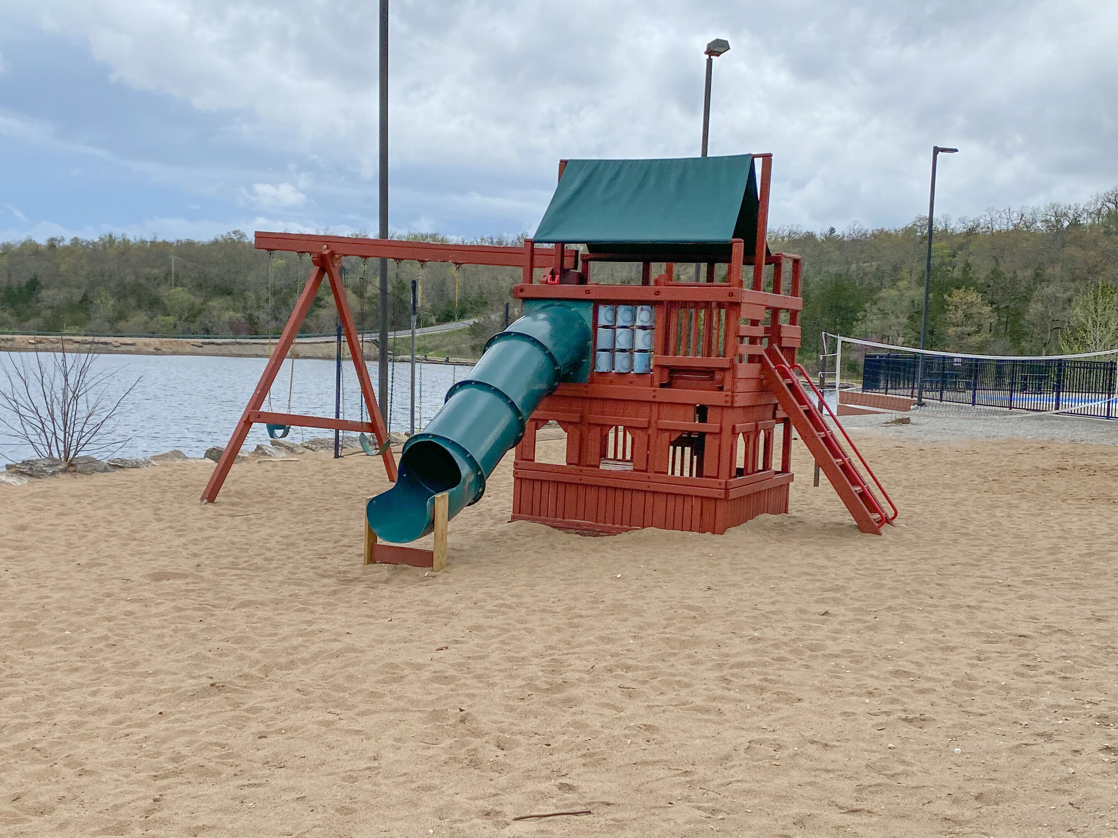 Un parque infantil con un tobogán y una estructura para escalar cerca del agua.