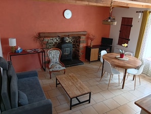 A cozy living room with a fireplace, a dining table with chairs, a sofa, and a television.