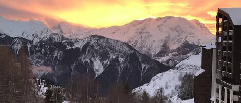 A mountain landscape with snow-covered peaks and a building with balconies.