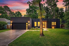 A modern two-story house with a garage, a well-maintained lawn, and a tree in the front yard. - CASA GRANADA - 5 Bed 4 Bath + FirePit + Patio + Large Backyard + TV's (Conroe)