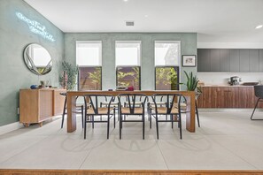 A modern kitchen with a dining area, large windows, and a neon sign. - CASA GRANADA - 5 Bed 4 Bath + FirePit + Patio + Large Backyard + TV's (Conroe)