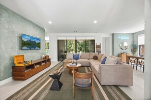 A modern living room with a sofa, coffee table, and a wooden cabinet. - CASA GRANADA - 5 Bed 4 Bath + FirePit + Patio + Large Backyard + TV's (Conroe)