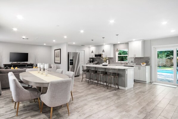 Una cocina moderna con una isla central, taburetes de bar y una zona de comedor con mesa y sillas.