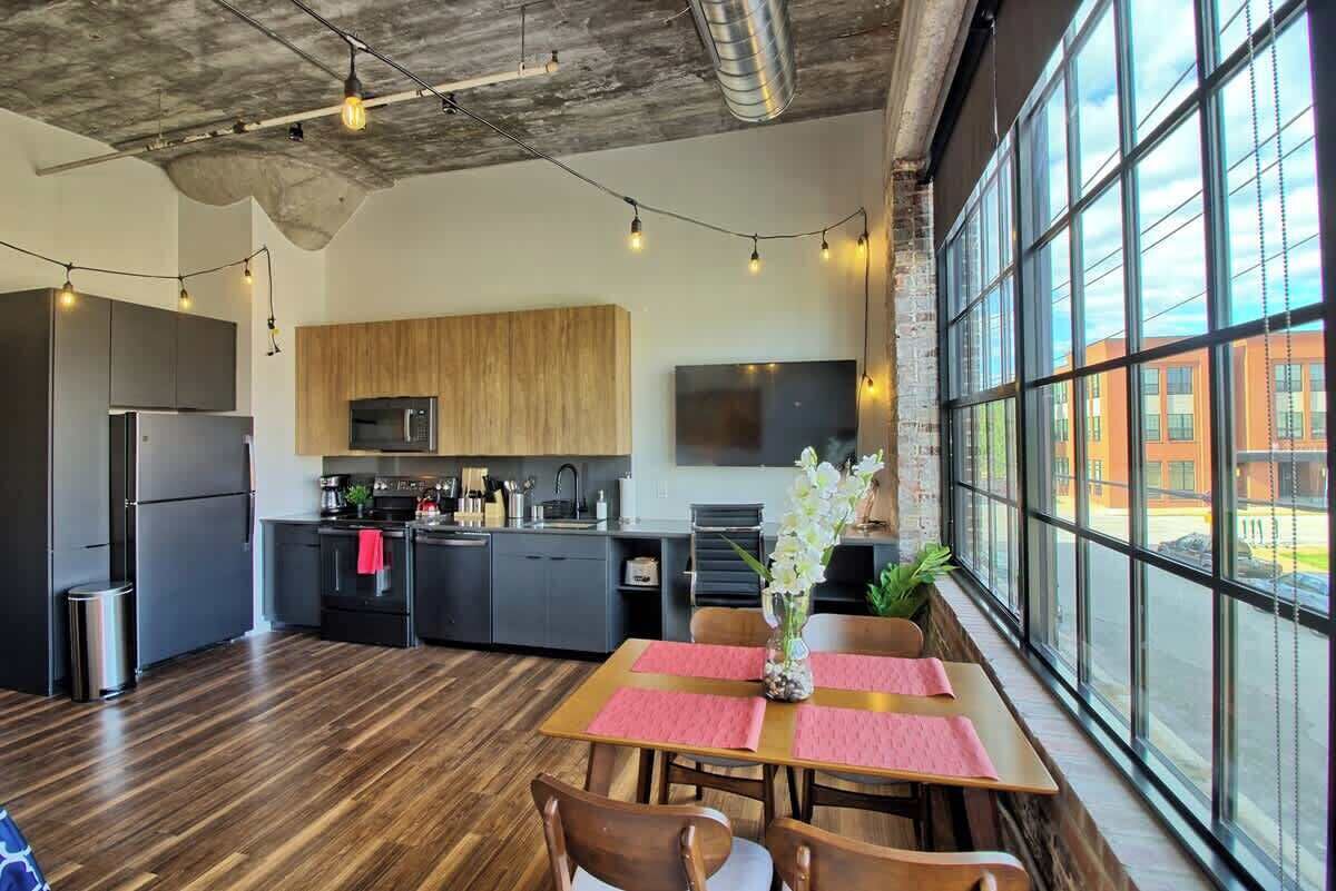 Una cocina moderna con un ventanal grande, armarios de madera y un comedor con mesa y sillas.